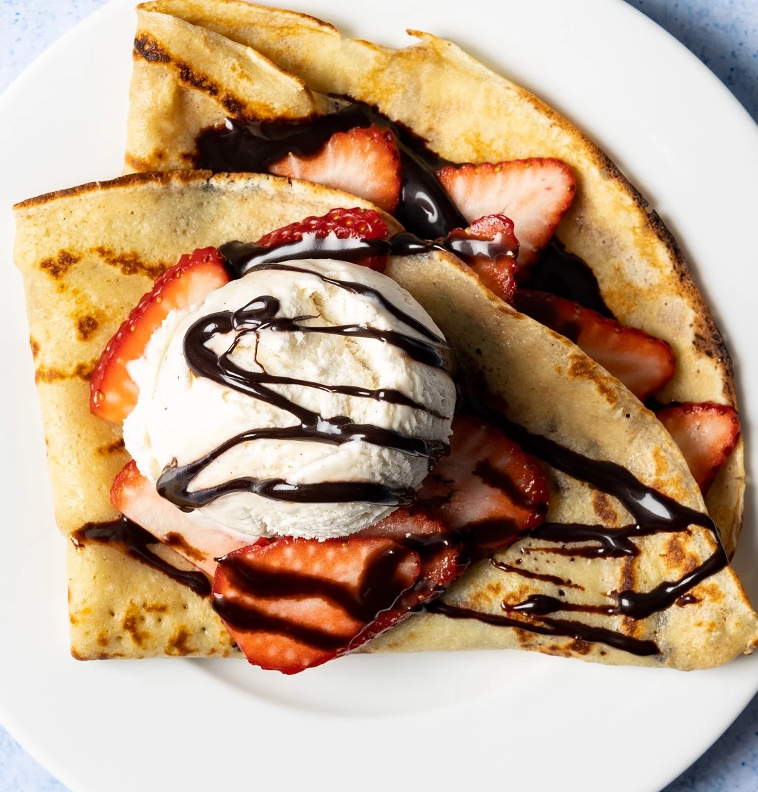 Hot crepe with ice cream, strawberries and chocolate sauce