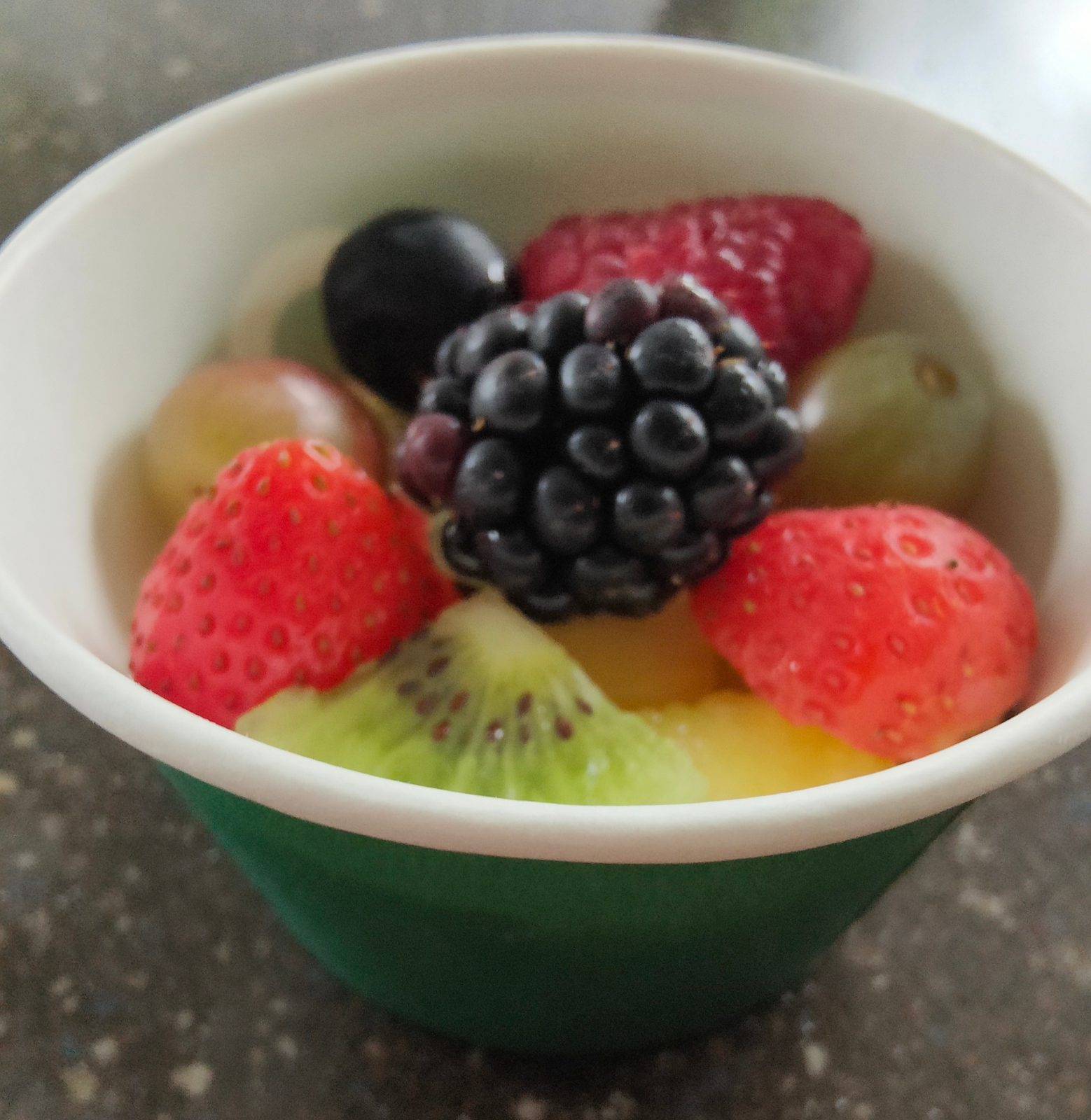 Fresh fruit bowl with strawberries, blackberry, grapes, kiwi and pineapple