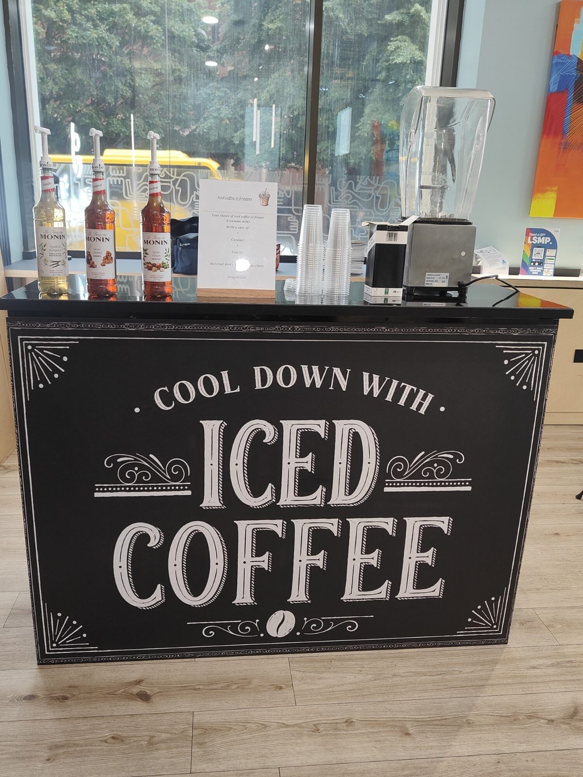 Iced coffee bar with vanilla, caramel and hazelnut syrups, cups and a blender set up at a corporate event