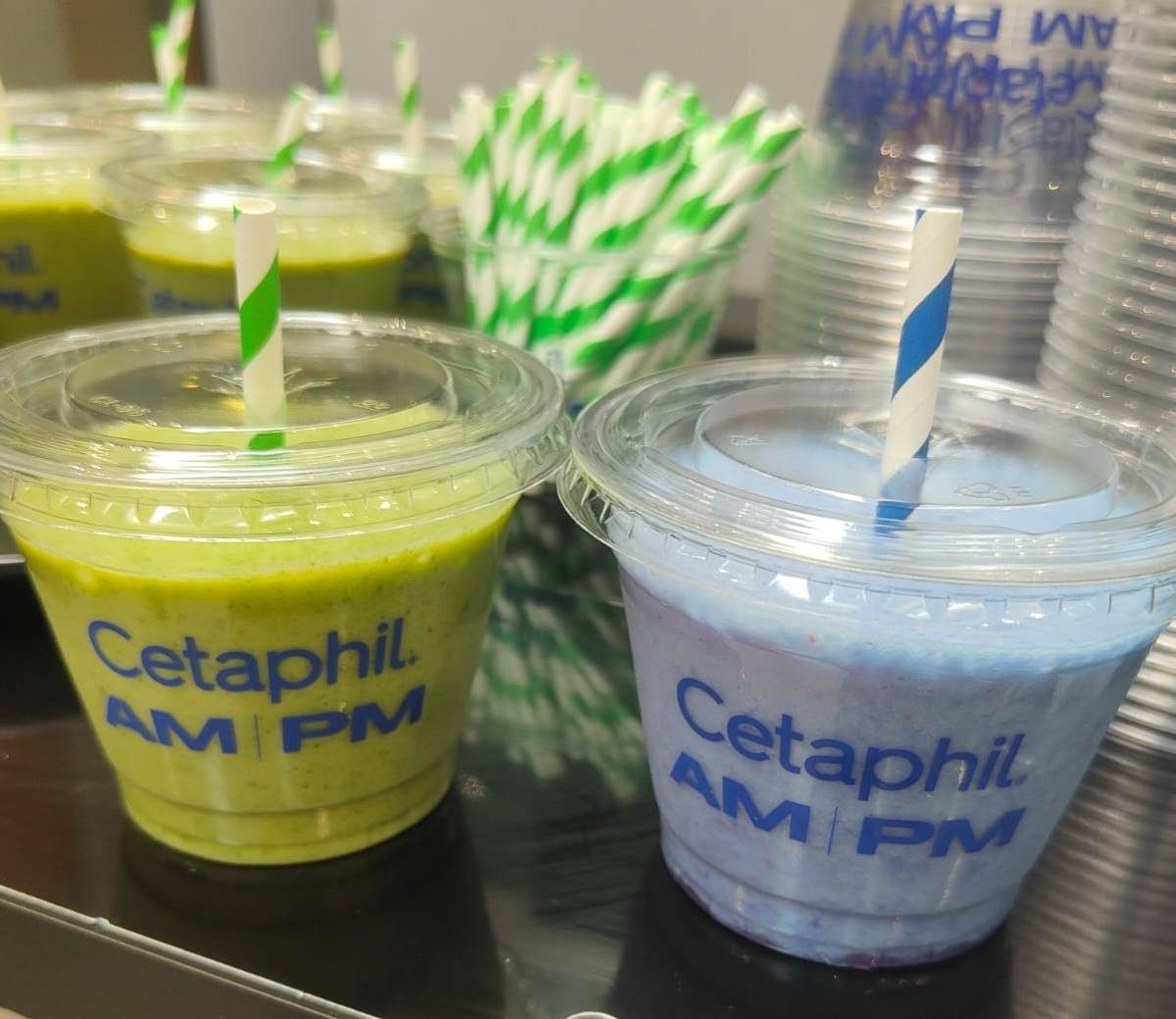 Green and blue smoothies in branded cups with striped paper straws