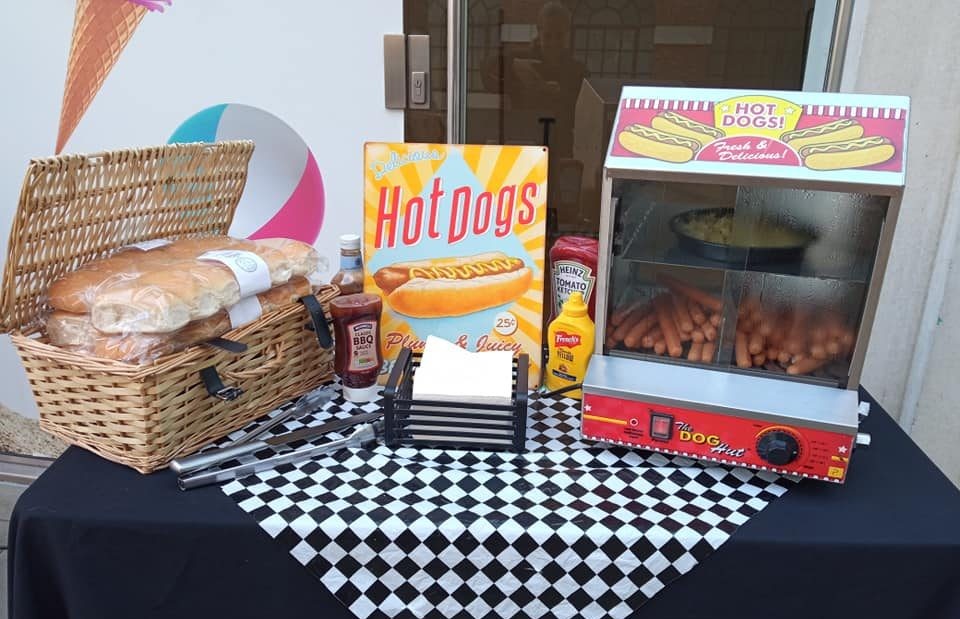 Hot dog machine set up with a basket of rolls, sauces and napkins