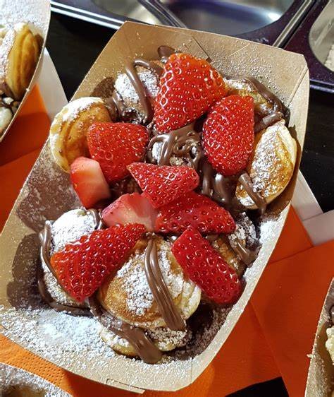 Mini Dutch pancakes topped with fresh strawberries, chocolate sauce and icing sugar